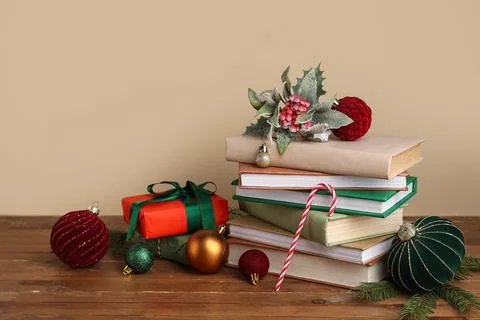 Stack of different books, Christmas balls and gift boxes on brown wooden tabl Stock Photos