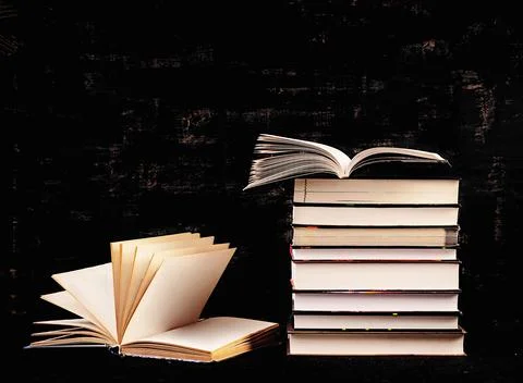 Stack of different books on dark background. Knowledge concept. Photos