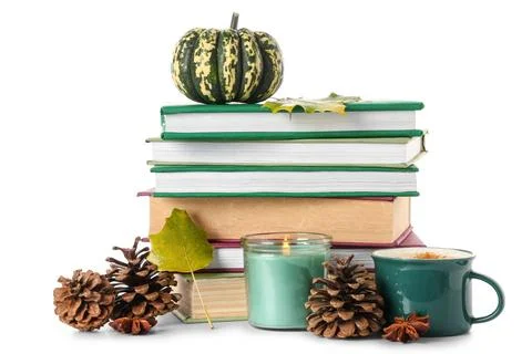 Stack of different books with pumpkin, cup of cocoa, burning candle, cones an Stock Photos