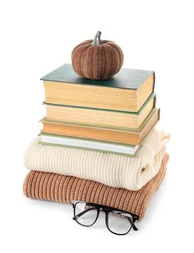 Stack of different books with sweaters, eyeglasses and decorative pumpkin on  Stock Photos