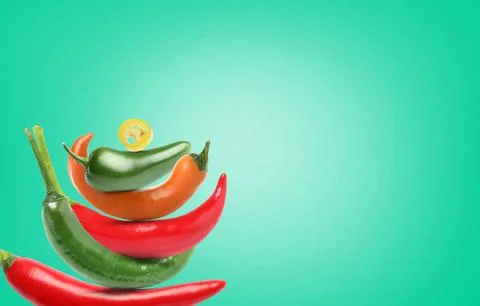 Stack of different chili peppers on turquoise background, space for text Stock Photos