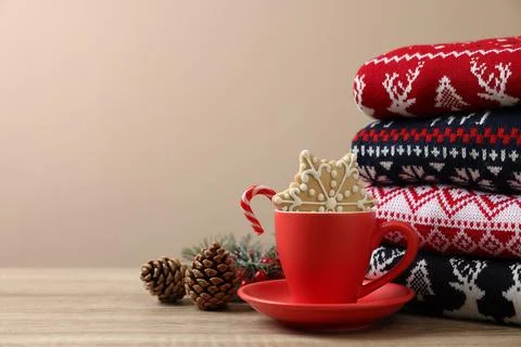 Stack of different Christmas sweaters, cup with candy cane, cookie and fest.. Foto stock