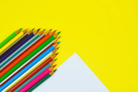 Stack of different colored pencil crayons arranged in a triangle shape row on Stock Photos