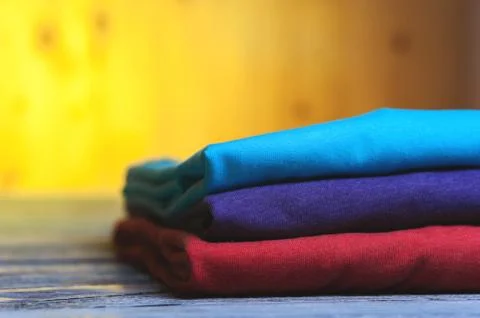 Stack of different cotton t-shirts on wooden table Stock Photos