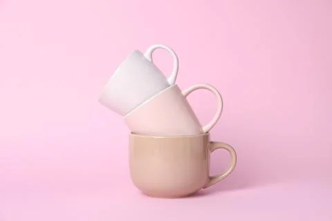 Stack of different cups on pink background Foto stock