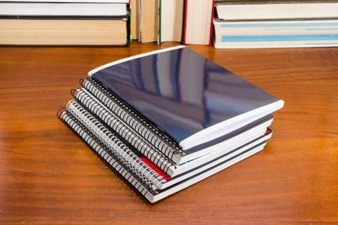 Stack of different exercise books on table against of books Stock Photos