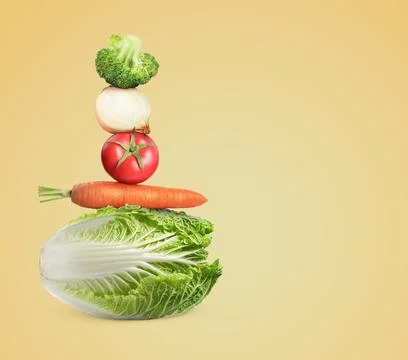 Stack of different fresh vegetables on light gold background, space for text Foto stock