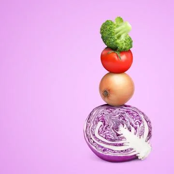 Stack of different fresh vegetables on violet background, space for text Stockfoto's