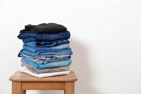 Stack of different jeans on table against white background. Space for text Foto stock