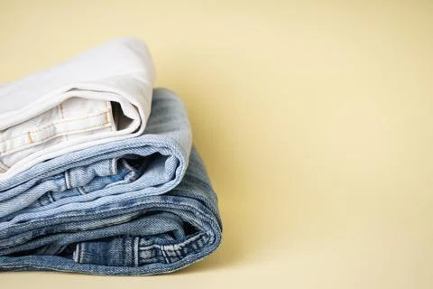 Stack different jeans on yellow background, space for text. Stock Photos