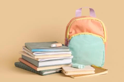 Stack of different notebooks with stationery and backpack on beige background Stock Photos
