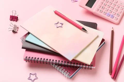 Stack of different notebooks with stationery and calculator on pink backgroun Stock Photos