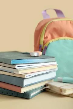 Stack of different notebooks with stationery and backpack on beige background Stock Photos