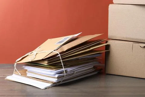 Stack of different paper envelopes and parcels on wooden table. Post office Foto stock