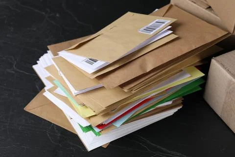 Stack of different paper envelopes and parcels on black table, closeup. Pos.. Stock Photos