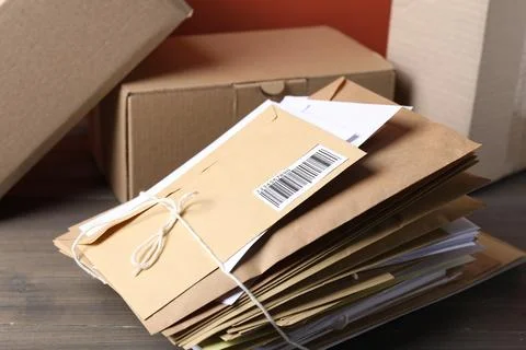 Stack of different paper envelopes and parcels on wooden table, closeup. Po.. Foto stock
