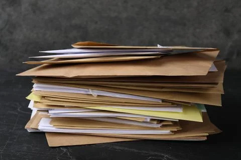 Stack of different paper envelopes on black table, closeup. Post office Foto stock