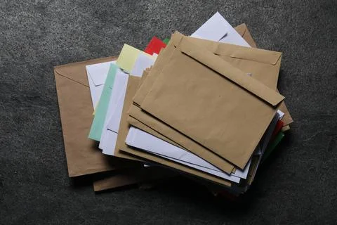 Stack of different paper envelopes on dark grey table, top view. Post office Foto stock