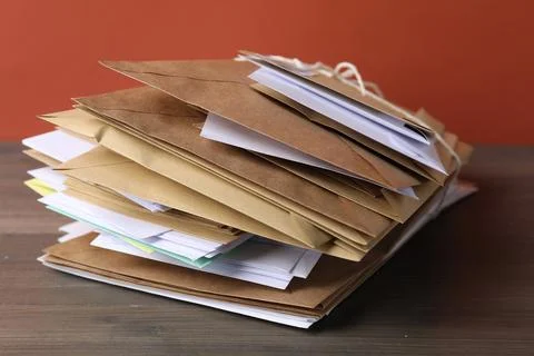 Stack of different paper envelopes on wooden table, closeup. Post office Foto stock