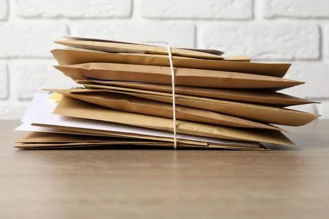 Stack of different paper envelopes on wooden table, closeup. Post office Foto stock