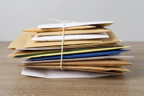Stack of different paper envelopes on wooden table, closeup. Post office Foto stock