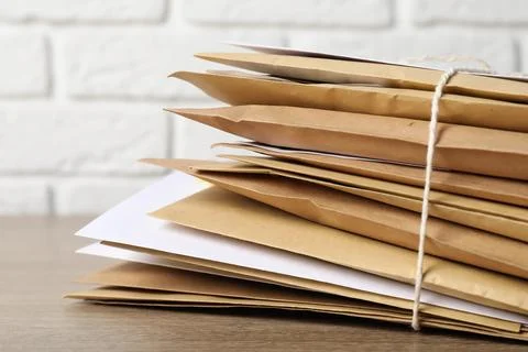 Stack of different paper envelopes on wooden table, closeup. Post office Foto stock