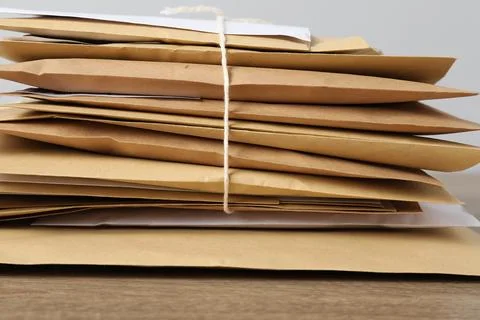 Stack of different paper envelopes on wooden table, closeup. Post office Foto stock