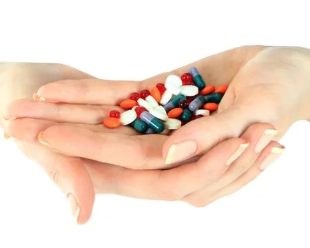 Stack of different pills in woman hands isolated over white Stock Photos