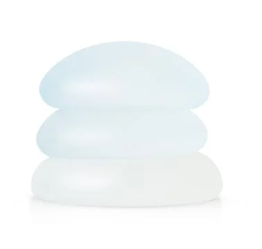 Stack of different types of breast implants isolated on white background. Stock Photos