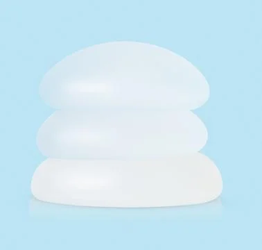 Stack of different types of breast implants on blue background. Stock Photos
