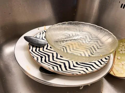 A stack of dirty dishes, including ceramic plates with patterns Stock Photos