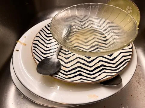 A stack of dirty dishes, including ceramic plates with patterns Stock Photos