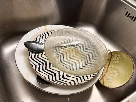 A stack of dirty dishes, including ceramic plates with patterns Foto stock