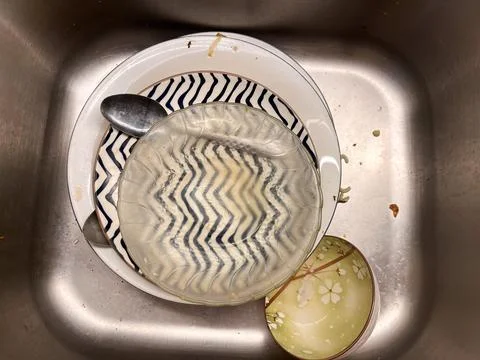 A stack of dirty dishes, including ceramic plates with patterns Stock Photos