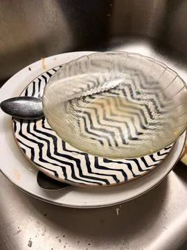 A stack of dirty dishes, including ceramic plates with patterns Foto stock