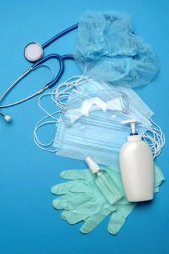 Stack of Disposable blue medical face masks, rubber latex gloves, goggles Stock Photos