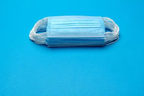 Stack of Disposable blue medical face masks on blue background Foto stock