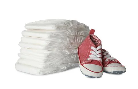 Stack of disposable diapers and child's shoes on white background 스톡 사진