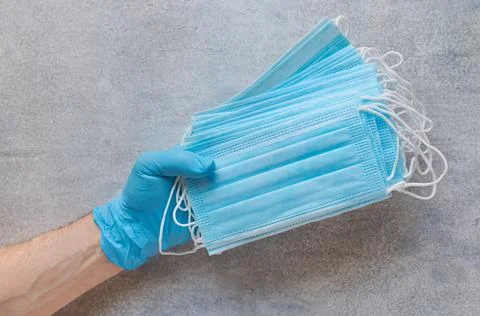 Stack of disposable medical protective masks in the hand Stock Photos