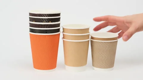 Stack of disposable paper cups for coffee and tea on a white background, hand pu Stock Footage 147548785