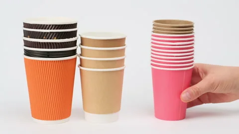 Stack of disposable paper cups for coffee and tea on a white background, hand pu Stock Footage 150232381