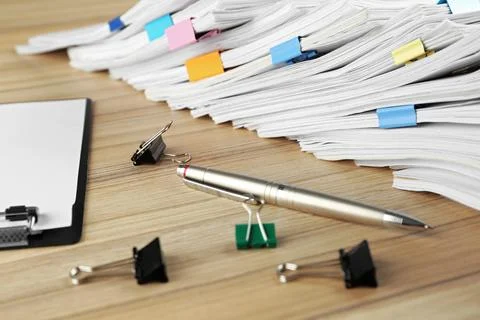 Stack of documents with binder clips, clipboard and pen on wooden table, clos Foto stock