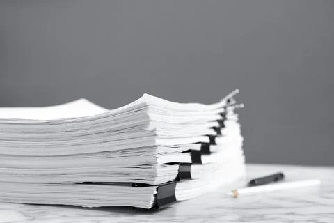 Stack of documents with binder clips on marble table against grey background 스톡 사진