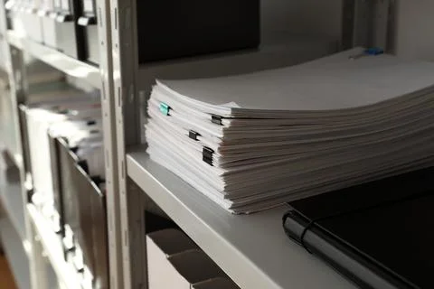 Stack of documents with paper clips on shelf in office Stock Photos