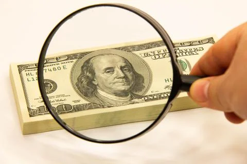 Stack of dollars under a magnifying glass. US dollar banknotes are enlarged Stock Photos