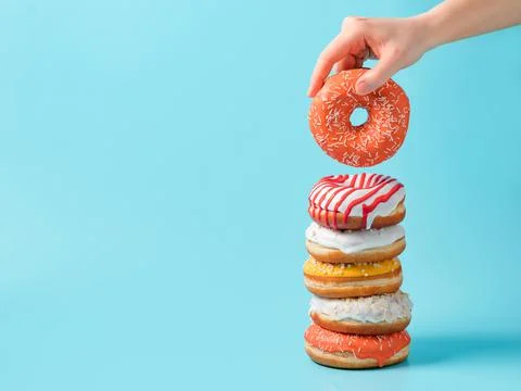 Stack of donuts, donut in hand on blue, copy space Foto stock