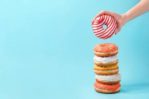 Stack of donuts, donut in hand on blue, copy space Stack of assorted donut... Foto stock