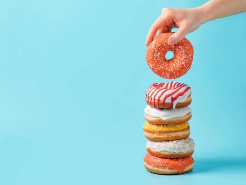 Stack of donuts, donut in hand on blue, copy space Stack of assorted donut... Foto stock