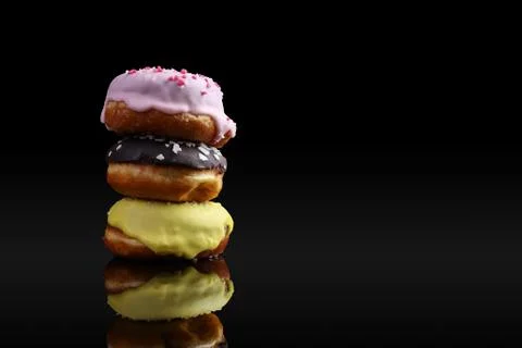 A stack of donuts with icing and chocolate powder, reflected in the mirror. O Stock Photos