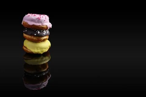 A stack of donuts with icing and chocolate powder, reflected in the mirror. O Stock Photos